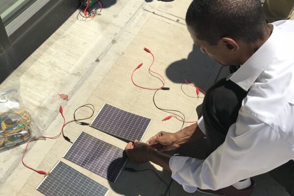 A young boy working on 3 small rectangular solar panels